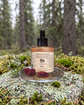 Crimson Rose Aphrodisiac Glow Oil on a lichen-covered granite stone on a boreal forest floor