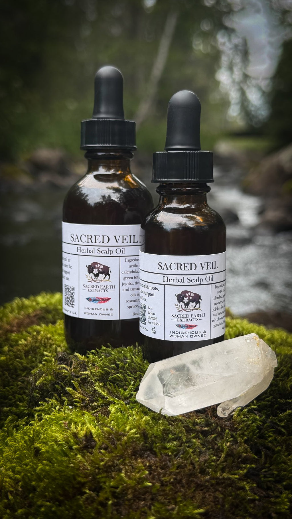 Two Sacred Veil herbal scalp oil bottles beside a stream