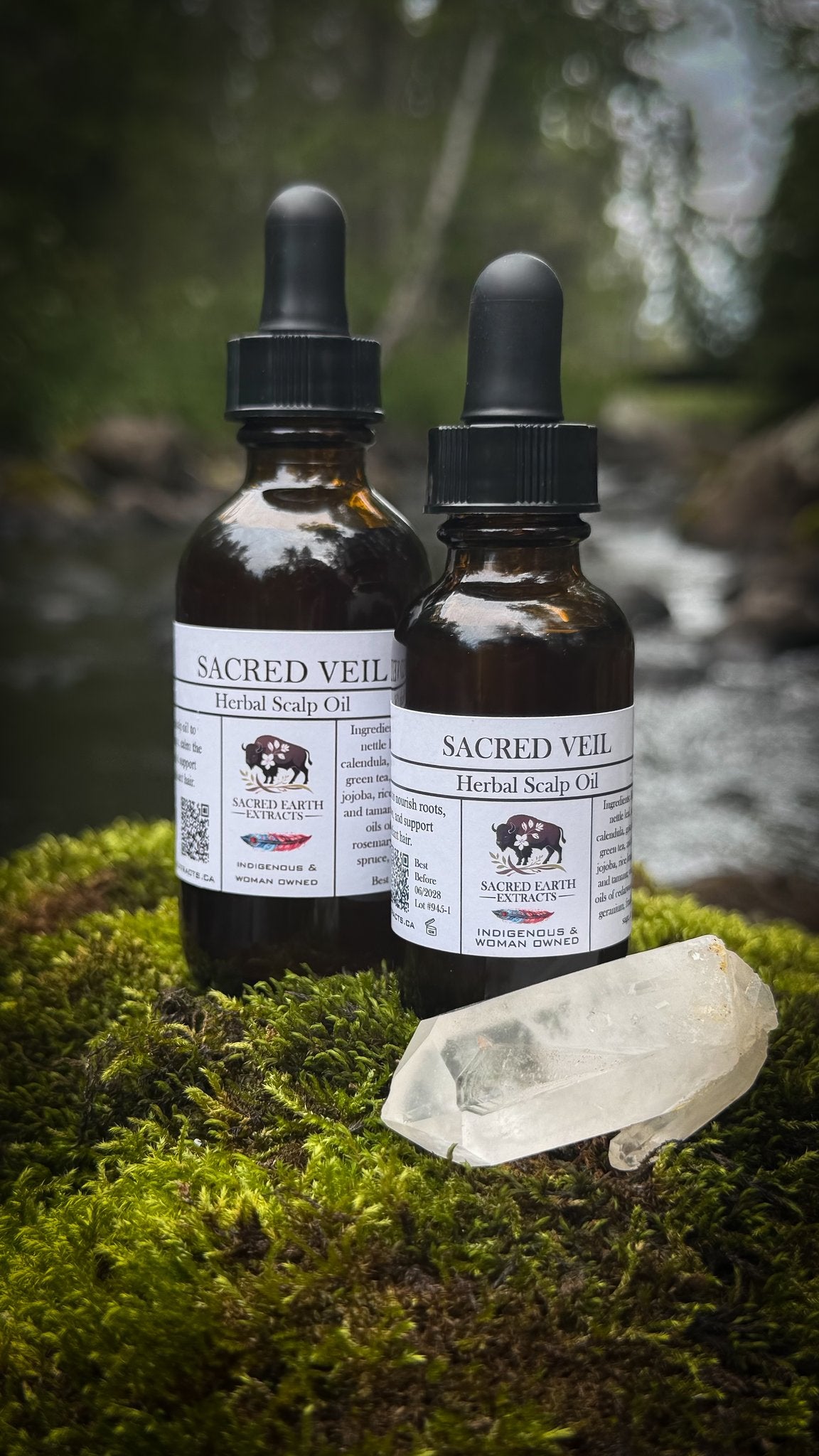 Two Sacred Veil herbal scalp oil bottles beside a stream